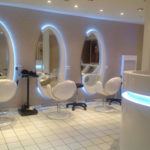 Salon de coiffure complet avec fauteuils et miroirs formes ovales et réception arrondie avec éclairage led intégrée